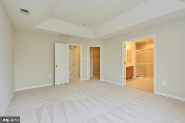 unfurnished bedroom with light colored carpet, visible vents, baseboards, ensuite bathroom, and a spacious closet