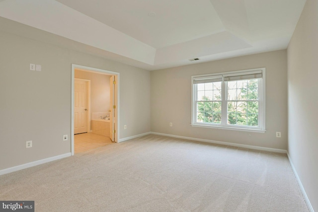 unfurnished room with baseboards, carpet, a tray ceiling, and visible vents
