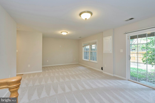empty room with visible vents, baseboards, and light colored carpet