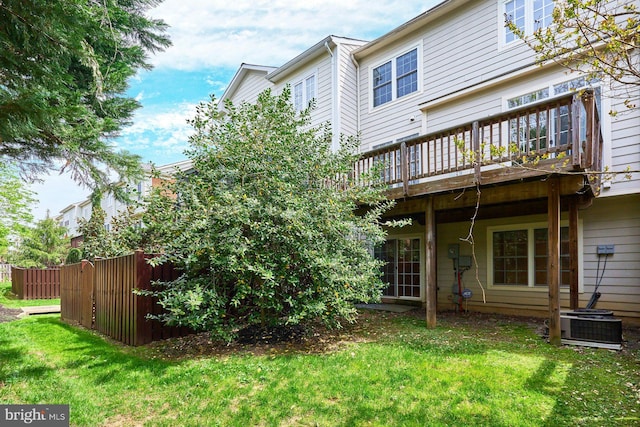 rear view of property with a lawn, fence, a deck, and cooling unit