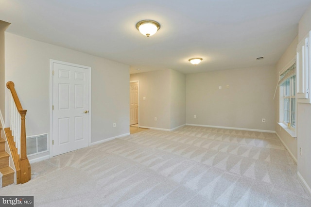 spare room with baseboards, light carpet, and visible vents