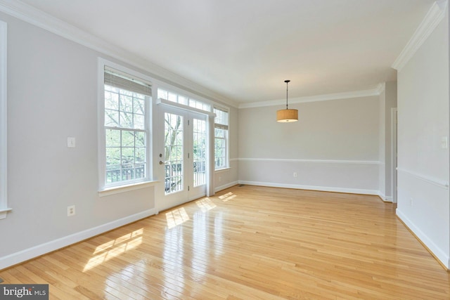 spare room with baseboards, ornamental molding, and light wood finished floors