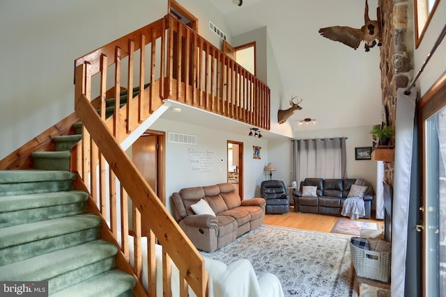 stairway featuring visible vents, a high ceiling, and wood finished floors