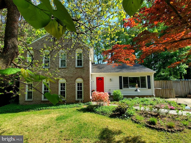 view of front of house featuring fence, a front lawn, and brick siding