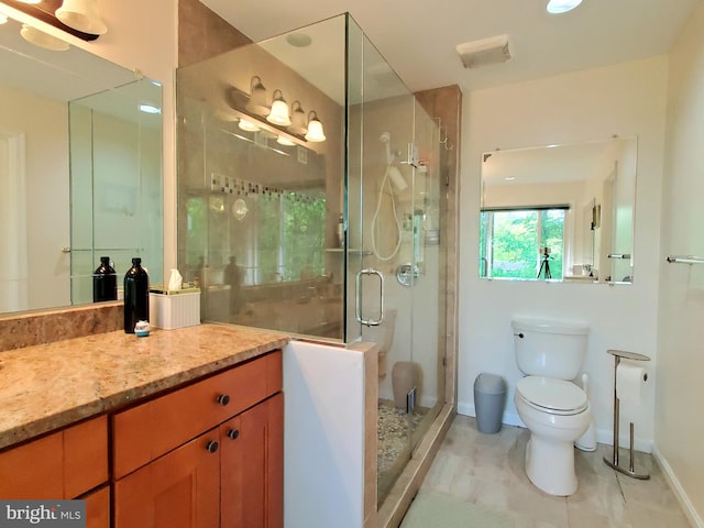 bathroom featuring vanity, toilet, tile patterned floors, baseboards, and a shower stall