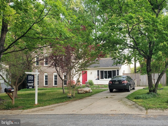view of front facade featuring fence, driveway, brick siding, and a front yard
