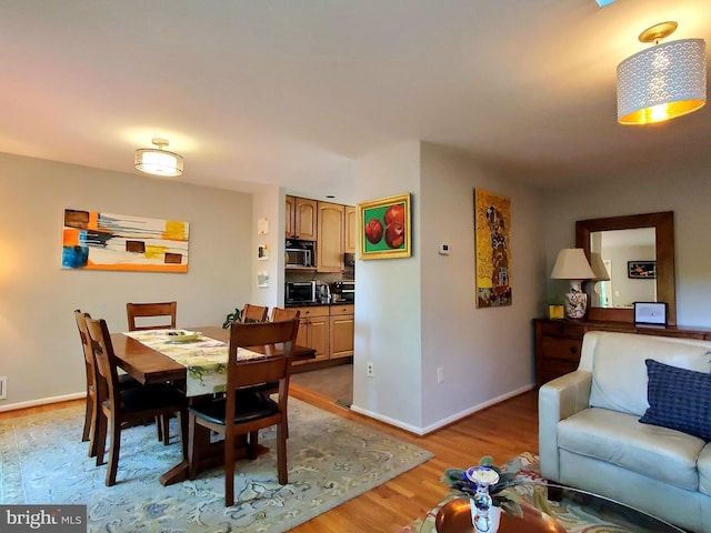 dining room with baseboards, a toaster, and light wood-style floors