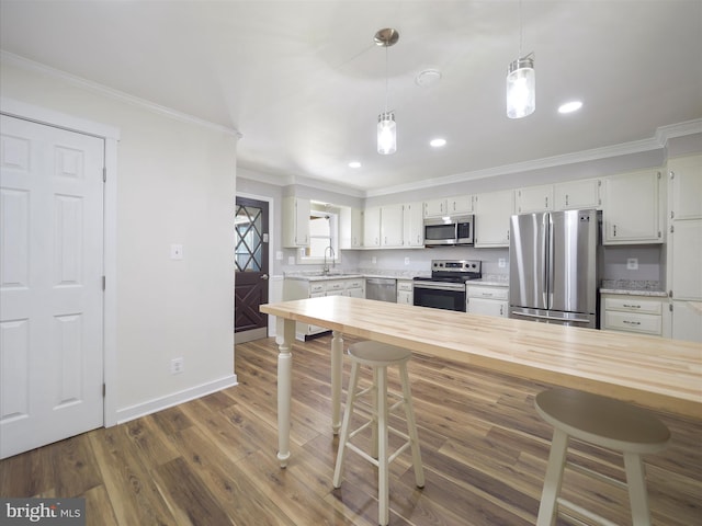 kitchen featuring ornamental molding, dark wood-style flooring, a kitchen breakfast bar, hanging light fixtures, and stainless steel appliances