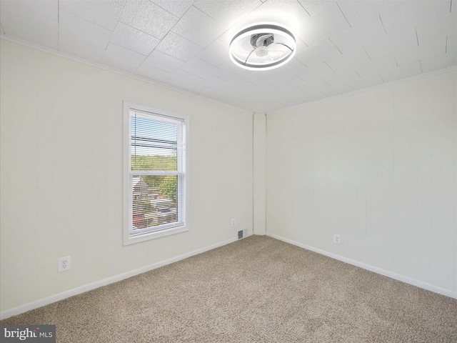carpeted empty room featuring visible vents, ornamental molding, and baseboards