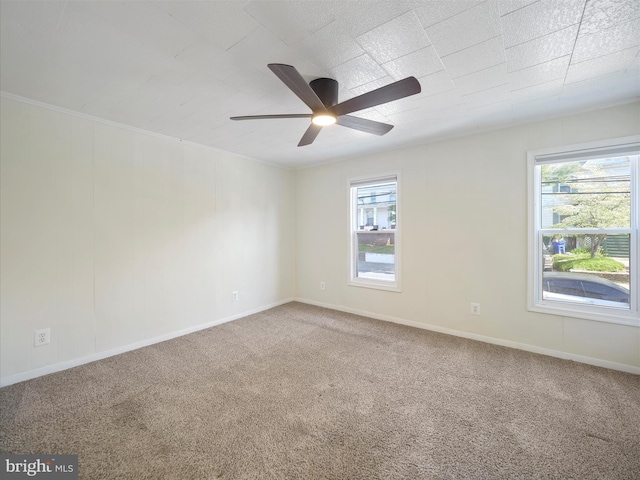 carpeted spare room with a ceiling fan, baseboards, and plenty of natural light