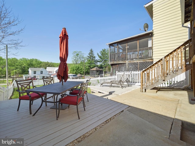 deck featuring outdoor dining area, a patio area, fence, and stairway