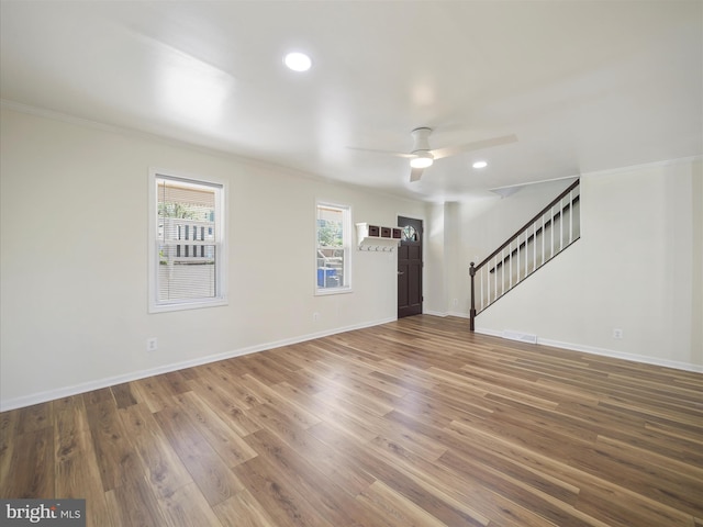 interior space with crown molding, stairs, wood finished floors, baseboards, and ceiling fan