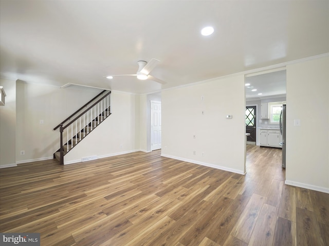 unfurnished living room with stairs, a ceiling fan, recessed lighting, and wood finished floors