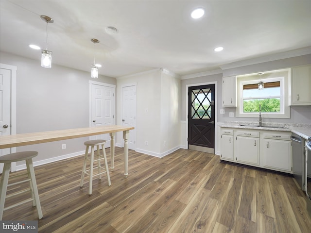 kitchen with a sink, white cabinets, ornamental molding, recessed lighting, and dark wood-type flooring