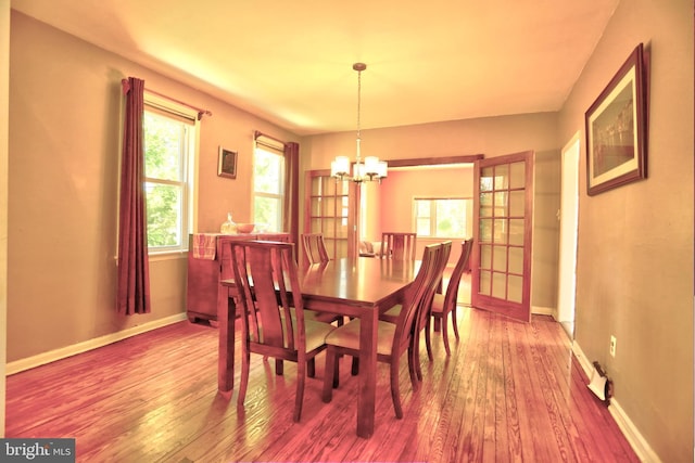 dining area with wood-type flooring, baseboards, and a chandelier