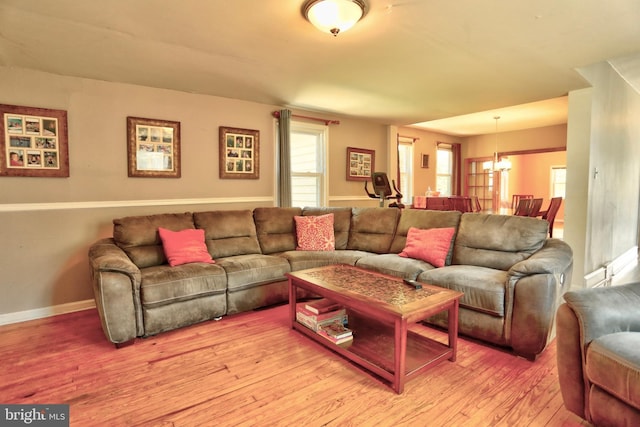 living area featuring light wood-type flooring, baseboards, and a notable chandelier
