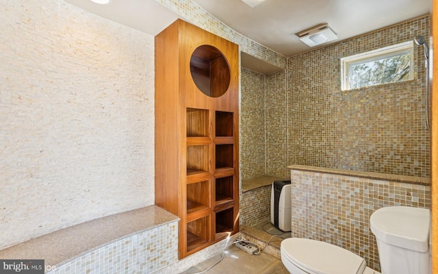 full bathroom featuring toilet, tile walls, tiled shower, and tile patterned floors
