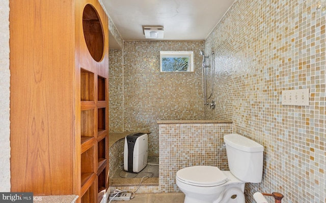 bathroom with toilet, a tile shower, tile walls, and tile patterned floors