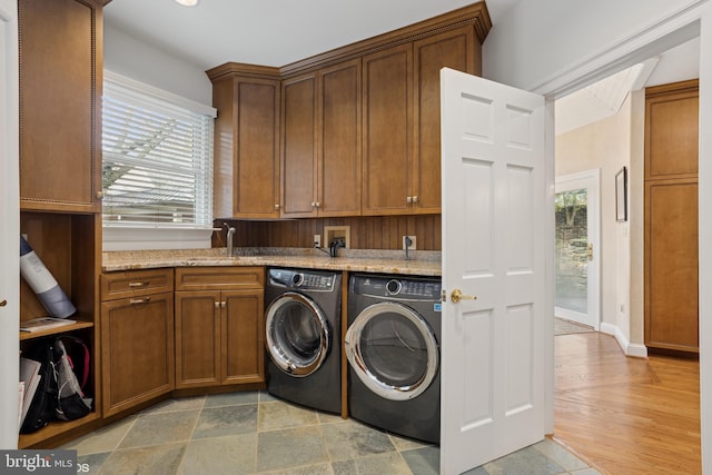 laundry room featuring washer and dryer, a wealth of natural light, cabinet space, and a sink