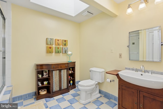 bathroom with toilet, vanity, a skylight, and a shower with door