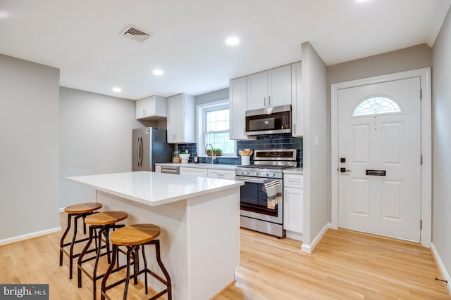 3306 Landover St, Alexandria, VA 22305 - kitchen featuring appliances with stainless steel finishes, a kitchen breakfast bar, light wood finished floors, tasteful backsplash, and a center island