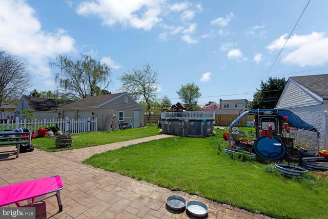 view of yard featuring a fenced in pool, a fenced backyard, a patio area, an outdoor structure, and an outdoor fire pit