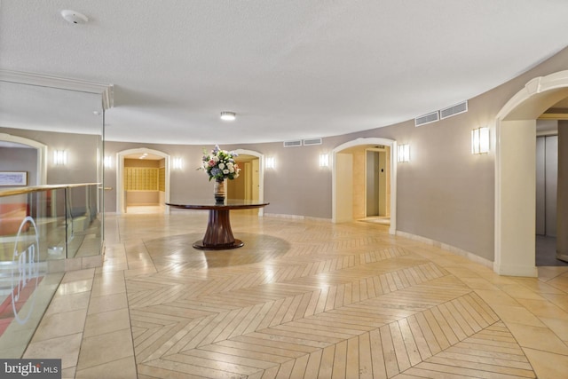 hallway with arched walkways, visible vents, and baseboards