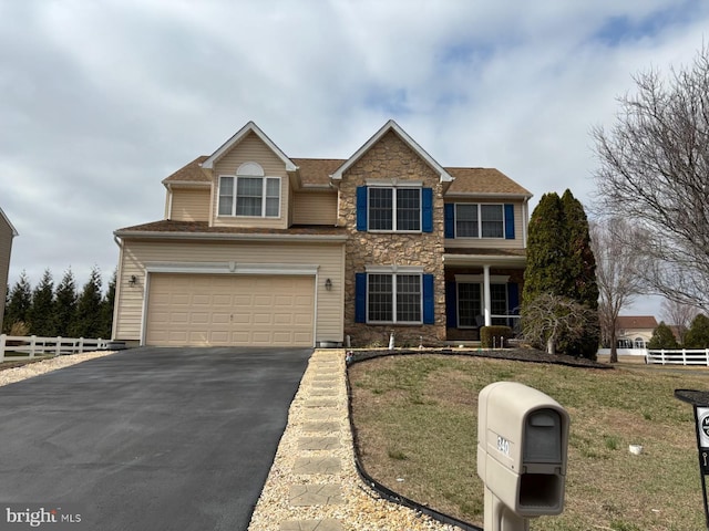 traditional-style house with a front yard, a garage, driveway, stone siding, and fence