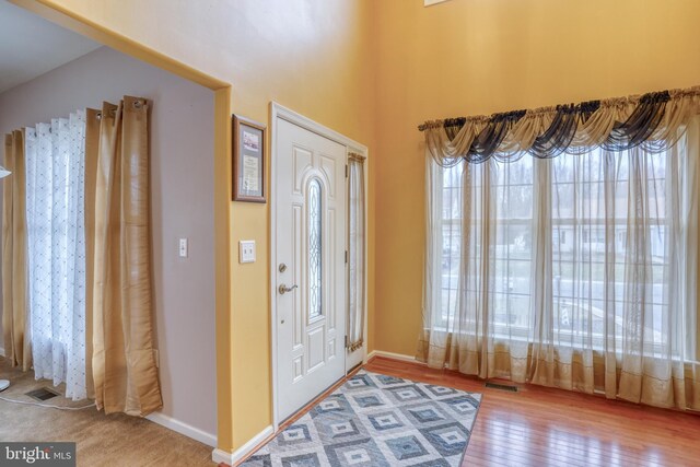 foyer entrance featuring baseboards, visible vents, and wood-type flooring