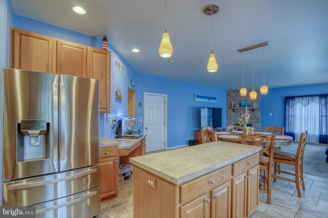 kitchen featuring a center island, stainless steel fridge with ice dispenser, pendant lighting, light countertops, and visible vents