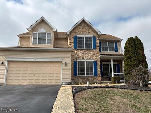 view of front facade with a garage, stone siding, and aphalt driveway