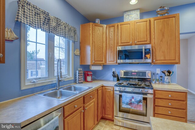 kitchen featuring appliances with stainless steel finishes, light countertops, and a sink