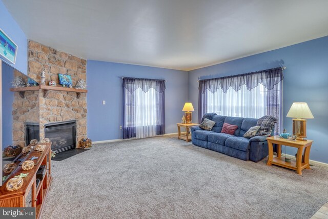 carpeted living room with a stone fireplace and baseboards