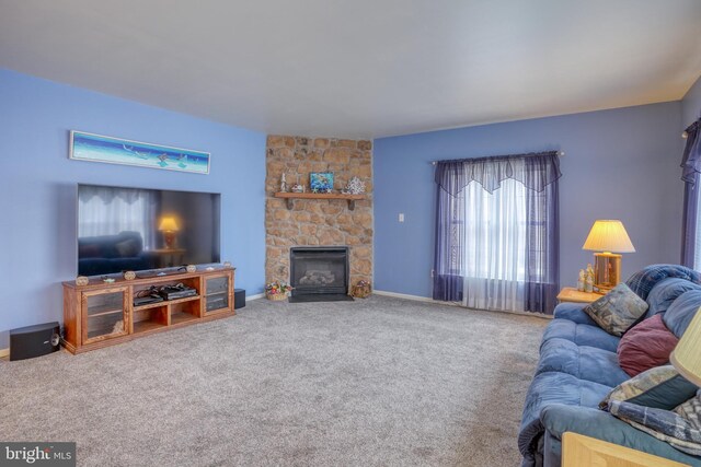 carpeted living room featuring baseboards and a stone fireplace