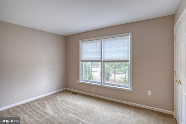 empty room featuring carpet, visible vents, and baseboards