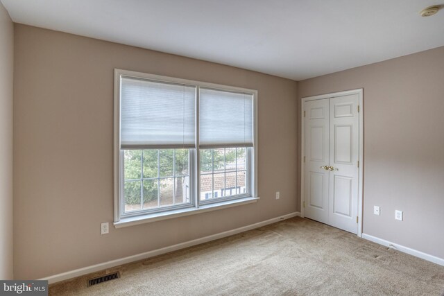 unfurnished bedroom with carpet flooring, visible vents, and baseboards
