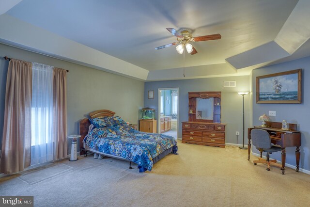 bedroom with a raised ceiling, visible vents, ensuite bathroom, and carpet floors