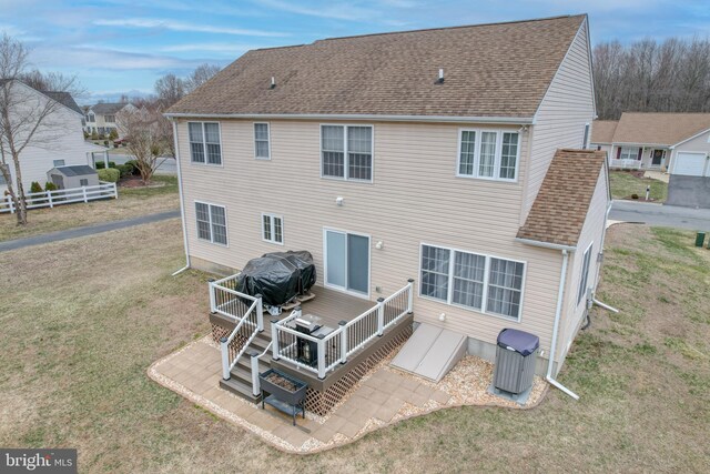 rear view of property with a lawn, a wooden deck, and a shingled roof