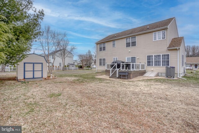back of house featuring a wooden deck, central AC unit, an outbuilding, a shed, and a lawn