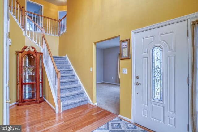 foyer entrance with baseboards, wood finished floors, stairs, and a towering ceiling