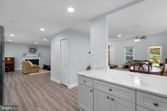 kitchen with light wood-style floors, open floor plan, recessed lighting, and light stone countertops