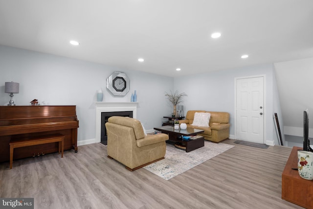 living room featuring recessed lighting, baseboards, a fireplace, and light wood-type flooring