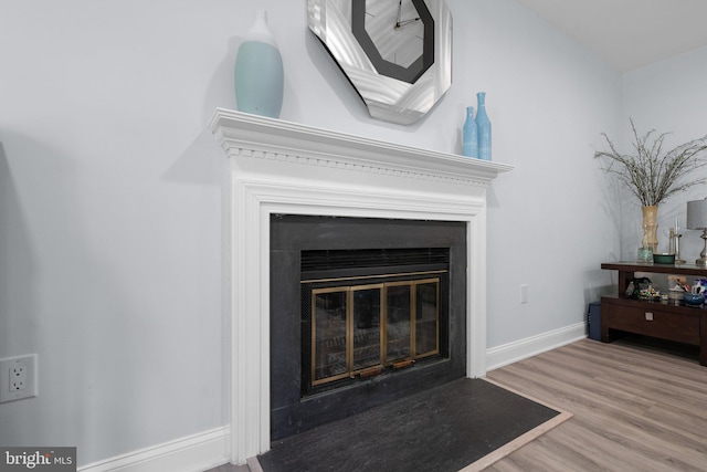 room details with a fireplace with flush hearth, baseboards, and wood finished floors