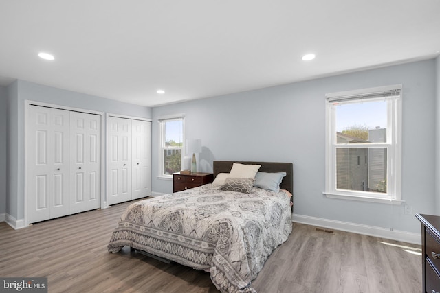 bedroom featuring multiple closets, baseboards, recessed lighting, and wood finished floors