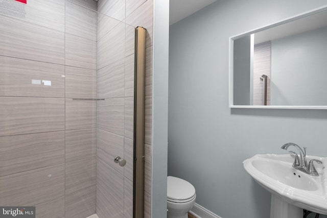 bathroom featuring a sink, a shower stall, and toilet