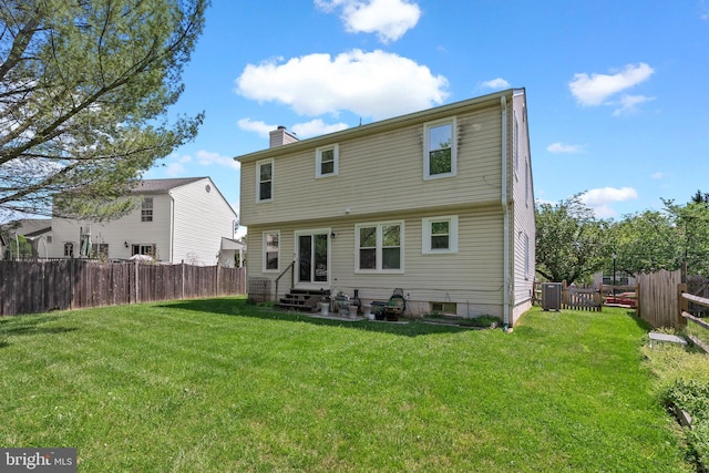 rear view of property with entry steps, a chimney, a yard, and a fenced backyard