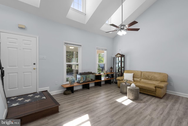 living area featuring a skylight, wood finished floors, and a towering ceiling