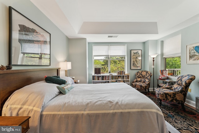 bedroom featuring a tray ceiling, baseboards, and visible vents
