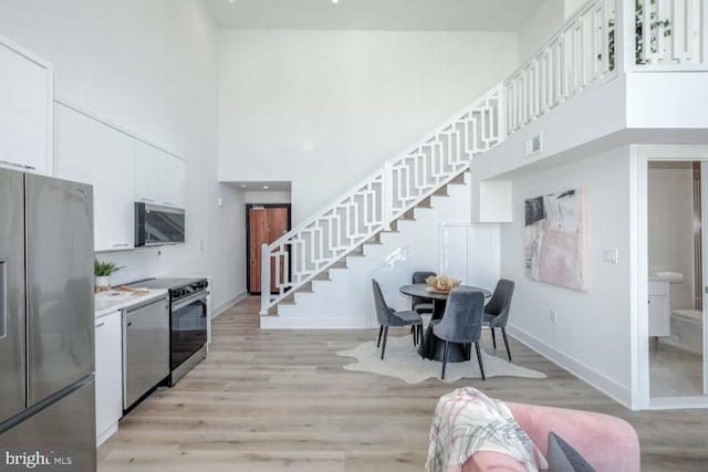 4328 Georgia Ave NW Unit 401, Washington, DC 20011 - kitchen featuring a high ceiling, visible vents, baseboards, appliances with stainless steel finishes, and white cabinetry