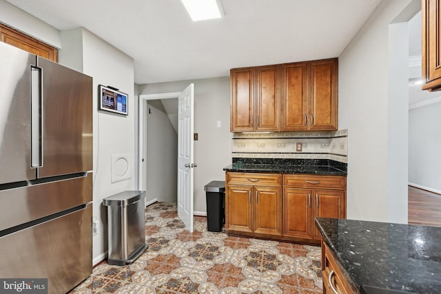 7112 Bonniemill Ln, Springfield, VA 22150 - kitchen featuring freestanding refrigerator, brown cabinets, dark stone counters, decorative backsplash, and tile patterned flooring